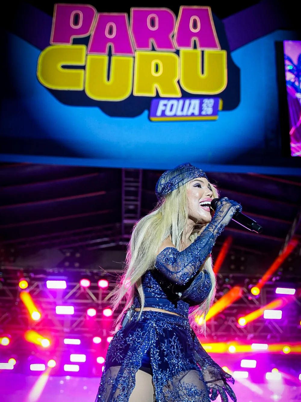 Jack Lins canta sob o painel do Paracuru Folia 2026, com luzes rosa e roxas no palco.