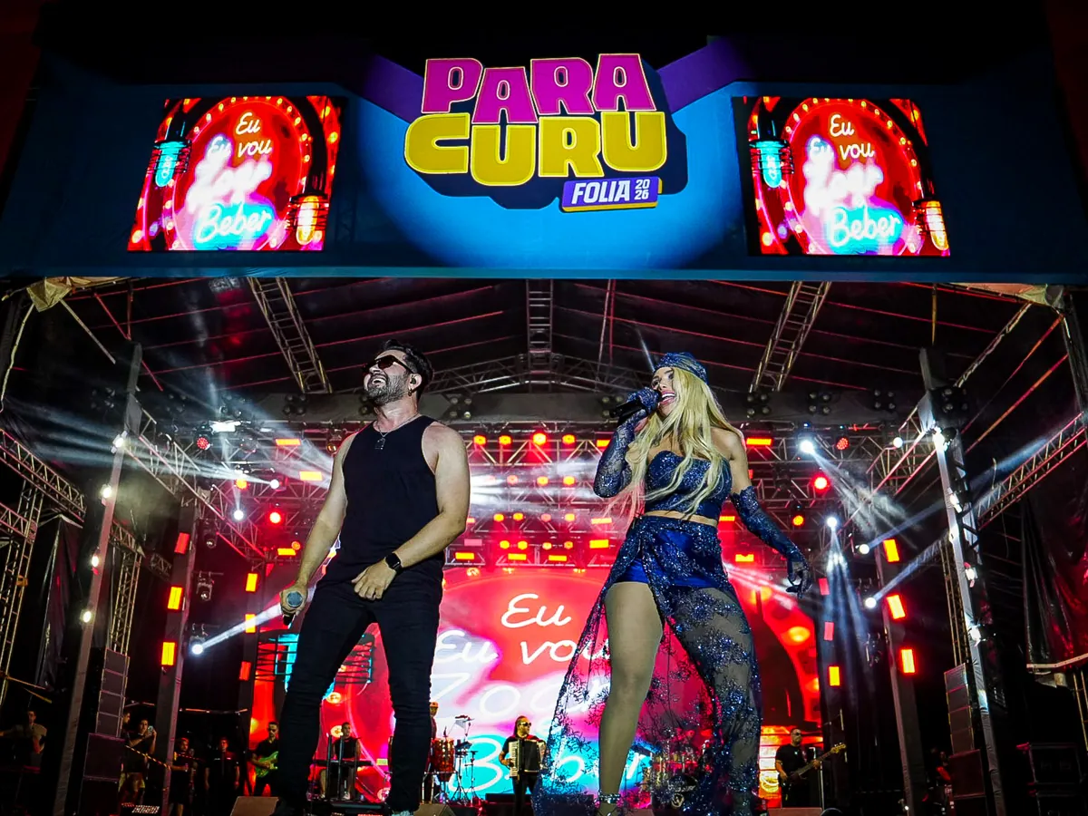 Léo Lira e Jack Lins cantam no palco do Paracuru Folia 2026, sob o painel do evento e dois telões.